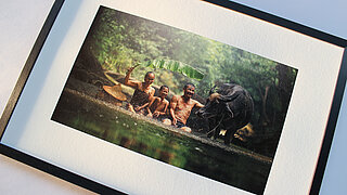 Framed picture of three people and a bull in a lake